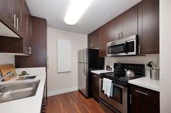 A kitchen with dark wood cabinets and stainless steel appliances.